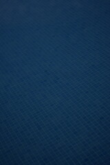 Blue ceramic tiles in a swimming pool, arranged in a small square mosaic pattern. The tile surface...