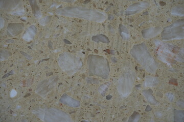 texture of polished stone terrazzo surface with natural mineral fragments. Beige background with brown and white stone chips creating an abstract decorative pattern. Ideal for flooring, countertops, a