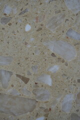 texture of polished stone terrazzo surface with natural mineral fragments. Beige background with brown and white stone chips creating an abstract decorative pattern. Ideal for flooring, countertops, a