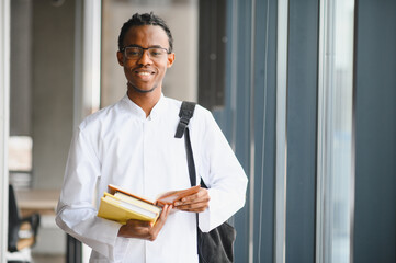 Smiling medical student holding books and notebook at university