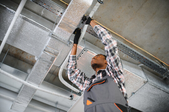 African American Hvac technician installing air duct, ensuring proper ventilation