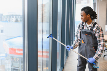 African American Professional cleaning service worker washing windows in office building
