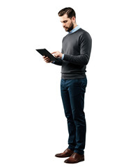 Young caucasian man, dark beard, in charcoal sweater, holding black digital tablet, silver stylus beside, on light grey studio background. Concept of modern business and technology