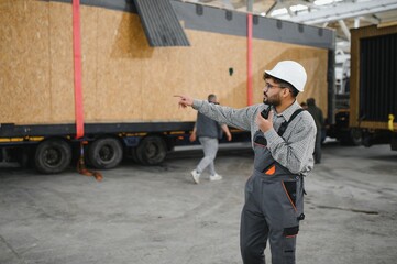 Arab engineer supervising prefabricated modular house transportation in construction workshop