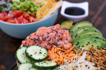 Colorful and fresh poke bowls with raw salmon, avocado, vegetables and seeds: healthy and balanced cuisine