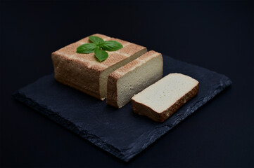 sliced ​​vegetarian tofu cheese on a cutting board on a dark background