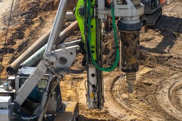 Heavy drilling rig machinery actively working on dusty construction site, preparing foundations...