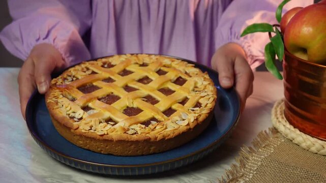 Placing a freshly baked fruit pie on a table decorated with apples in a cozy setting