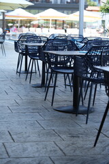 Outdoor hotel terrace with modern blue mesh plastic chairs and white dining tables – empty restaurant patio furniture close up on stone floor, stylish hospitality design and contemporary travel concep
