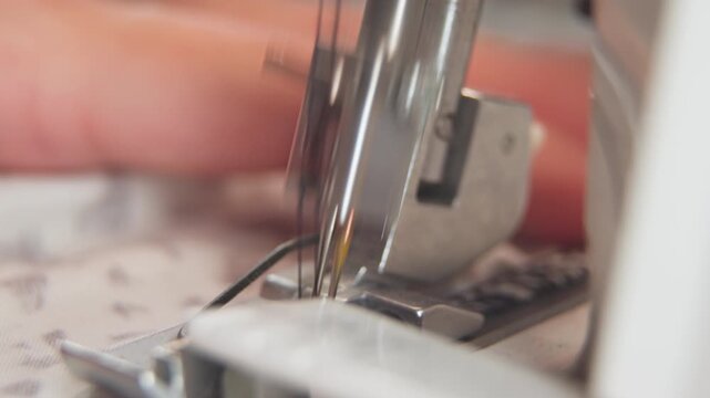 Female hands of seamstress sewing clothes on sewing machine in sewing workshop, close-up. Concept Emphasis on manual work and attention to detail.