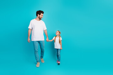 Single father holding hands with his little daughter on a cheerful turquoise background emphasizing family love and bonding