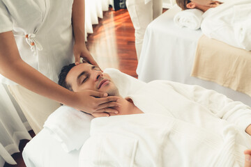 Obraz premium Caucasian couple enjoying relaxing anti-stress head massage and pampering facial beauty skin recreation leisure in dayspa modern light ambient at luxury resort or hotel spa salon. Quiescent