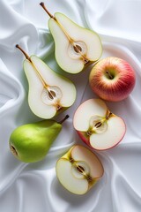 Fresh pears and apples artfully arranged on soft white fabric, perfect for food photography and healthy lifestyle concepts.