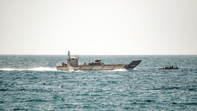 Two military landing craft speed across the sea during naval amphibious training exercises