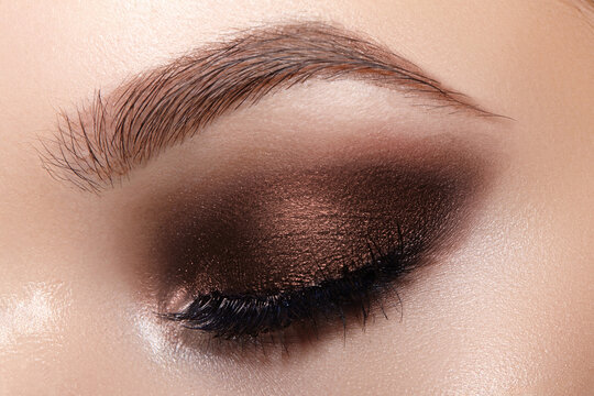 Macro beauty of eye makeup. Beautiful fashion evening eyes make-up. Holiday makeup detail with long eyelashes and perfect brow. Close-up of festive female eye make up in smokey eyes style