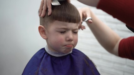 child squinting during haircut at barber