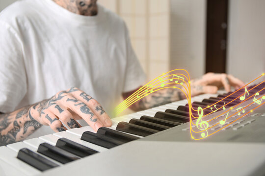 Young tattooed man playing synthesizer at home, closeup
