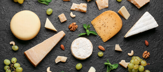 Different types of tasty cheese, grapes and nuts on dark background