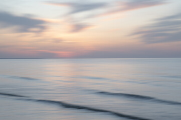 A dreamy, impressionistic paint like blurred sea sunset background with gently soft pastel colours. Vertical photo.