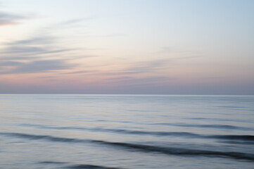 A dreamy, impressionistic paint like blurred sea sunset background with gently soft pastel colours. Vertical photo.