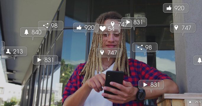 Leaning man with dreads in plaid shirt scrolling smartphone on balcony with floating social icons - Powered by Adobe