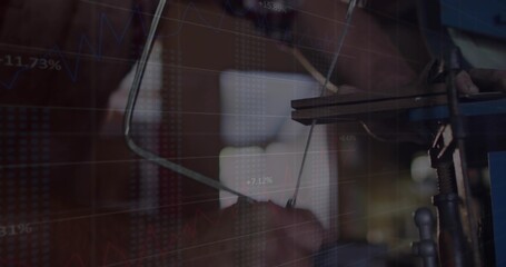 Operating machinist adjusting drill-press lever at workshop, showing floating stock chart overlay