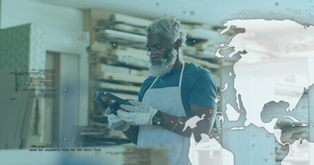 Cobbler wearing gloves holding and examining shoe sole in workshop, with wooden lasts, digital map