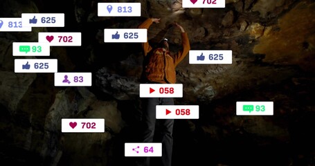 Exploring man wearing orange coat, helmet headlamp illuminating cave walls, with social media icons