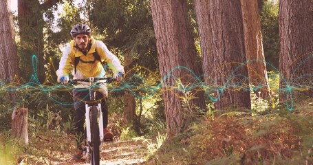 Cyclist wearing helmet, yellow jacket riding mountain bike on pine trail, with digital overlay