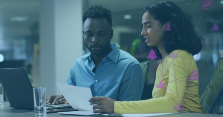 Collaborating coworkers reading document and typing at office meeting room, with laptop computer