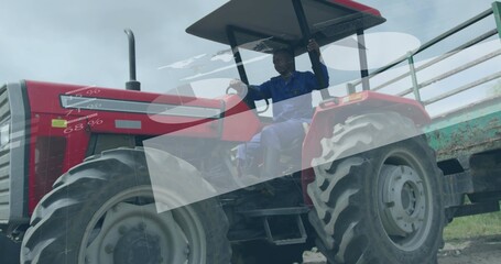 Driving operator wearing blue coveralls on dirt track, with red tractor and green metal trailer