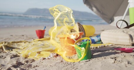 Naklejka premium Arranging colorful sand buckets and shovel on sunny beach shore, with striped towel and cooler bag