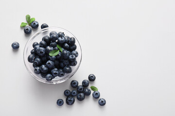 Glass bowl of fresh ripe blueberry on white background