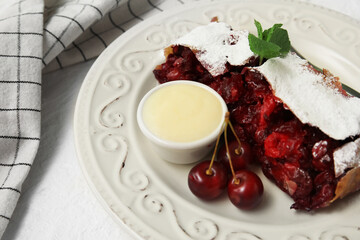 Plate with piece of tasty cherry strudel and napkin on white background, closeup
