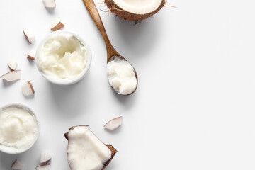Bowls and wooden spoon of coconut butter on grey background