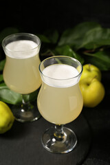 Glasses of fresh apple kvass and fruits on black background