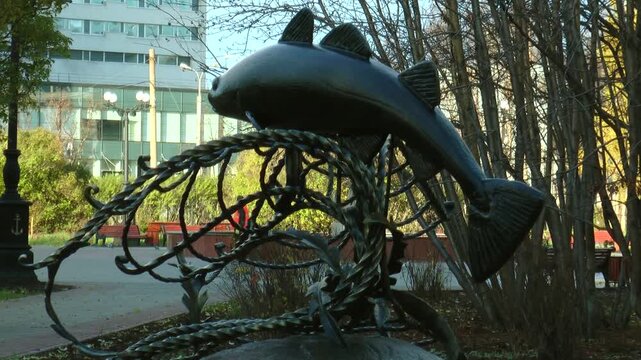 Copper statue depicting caught in the nets of cod in autumn the park.
