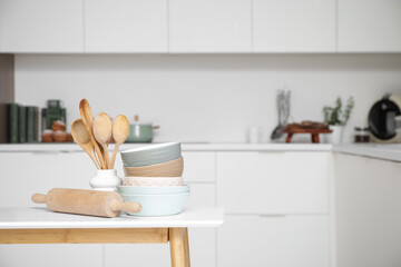Wooden spoons with rolling pin and bowls on table in kitchen, closeup