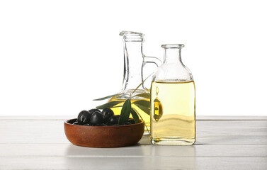Decanter and bottle of fresh olive oil on wooden table against white background
