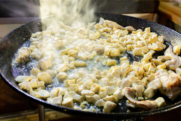 Sizzling chicken pieces cooking in large paella pan