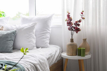 Vases with eucalyptus branches and candles on table in light bedroom © Pixel-Shot