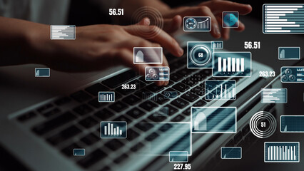 A close-up view of hands typing on a laptop keyboard, surrounded by dynamic digital graphs and statistics overlays, symbolizing data-driven technology and business insights. Xenic