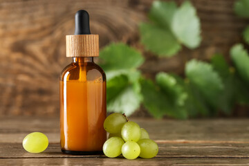 Bottle of cosmetic grape seed oil on wooden background