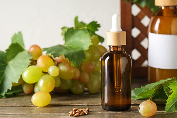 Bottles of cosmetic grape seed oil on wooden table