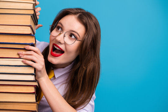 Happy student with stack of book expressing excitement on vibrant blue background showcasing enthusiasm for learning.