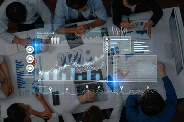 A business team collaborates over data analysis with modern technology dashboards and graphs on the table, enhancing strategic decision-making and performance insights. Trope