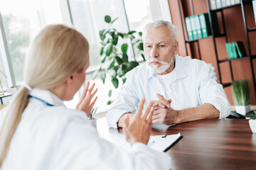 Obraz premium Doctor consulting an elderly patient in a modern clinic, addressing health concerns and providing medical advice