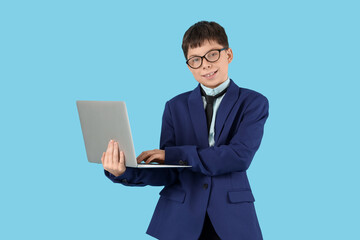 Teenage businessman using laptop on blue background