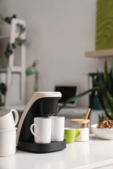 Coffee machine with cups on table in office, closeup