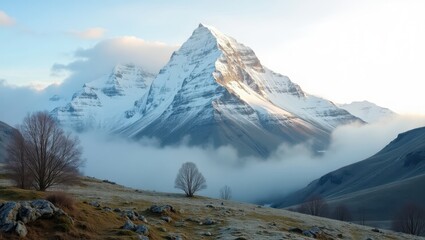 A breathtaking vista of snow-capped mountains shrouded in a tranquil blanket of mist, revealing a serene landscape of barren trees and rocky terrain.